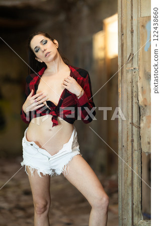 Woman in unbuttoned shirt and shorts in abandoned building 122438660