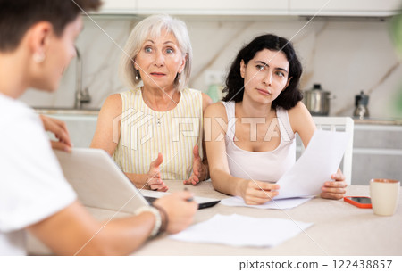 Elderly and young female clients listen attentively and intently to male seller Elderly and young female clients listen attentively and intently to male seller 122438857