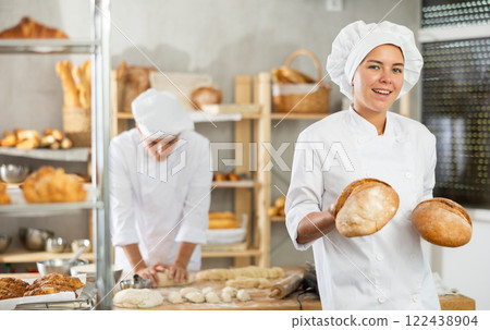 Young female baker holding bread in square wicker basket 122438904
