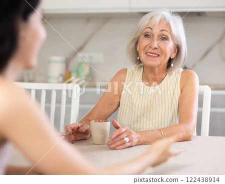 Young woman and elderly woman drinking tea in kitchen Young woman and elderly woman drinking tea in kitchen 122438914