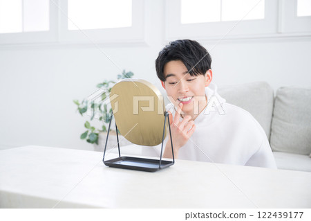 Looking in the mirror, image of teeth whitening, alignment, and orthodontics - Young man in his 20s Looking in the mirror, image of teeth whitening, alignment, and orthodontics - Young man in his 20s 122439177