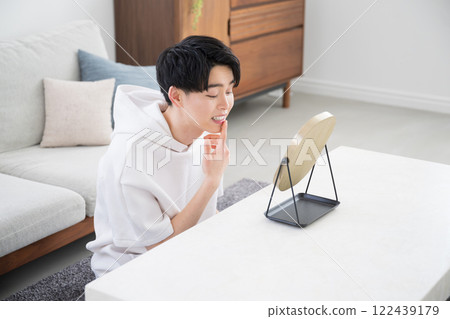 Looking in the mirror, image of teeth whitening, alignment, and orthodontics - Young man in his 20s Looking in the mirror, image of teeth whitening, alignment, and orthodontics - Young man in his 20s 122439179