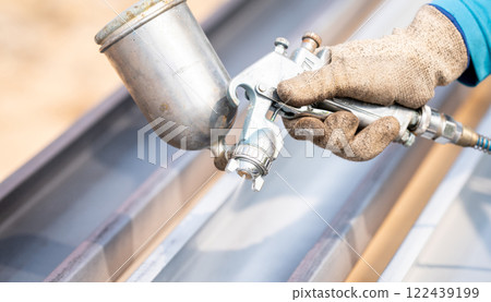 Construction worker painting metal structure surface coating with a spray gun at construction site. Metal corrosion and rust protection. Industrial precision. Protective coating to a metal structure. Construction worker painting metal structure surface coating with a spray gun at construction site. Metal corrosion and rust protection. Industrial precision. Protective coating to a metal structure. 122439199