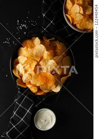Potato chips in a black bowl on a dark background 122440454