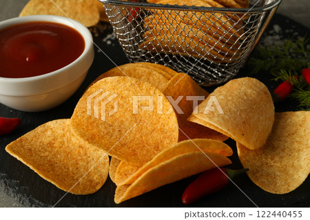 Potato chips with sauce and chili pepper on a dark background Potato chips with sauce and chili pepper on a dark background 122440455