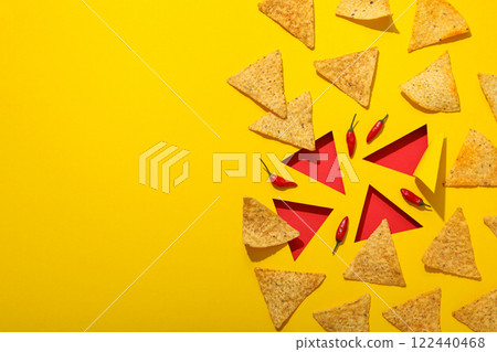 Triangular potato chips with chili pepper on a yellow background 122440468