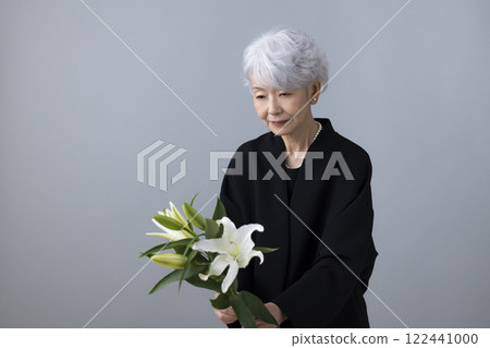 Senior woman wearing mourning clothes and holding a lily flower Senior woman wearing mourning clothes and holding a lily flower 122441000