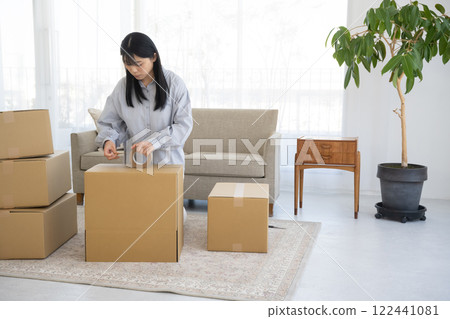 女人把膠帶貼在紙箱上 女人把膠帶貼在紙箱上 122441081
