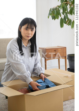 Woman packing clothes into cardboard boxes 122441102