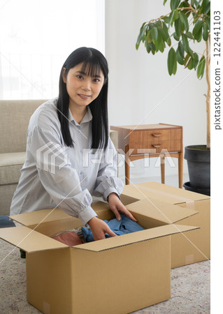 Woman packing clothes into cardboard boxes 122441103