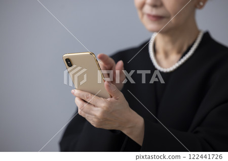 喪服：老年婦女的手看著智慧型手機 122441726
