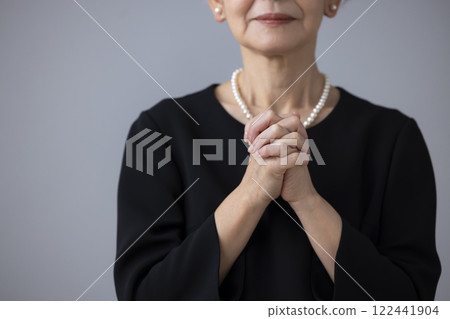 Hands of a senior woman praying in mourning clothes 122441904