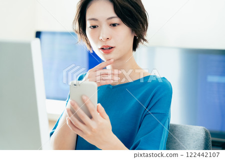 操作一個智能手機的少婦在辦公室 122442107