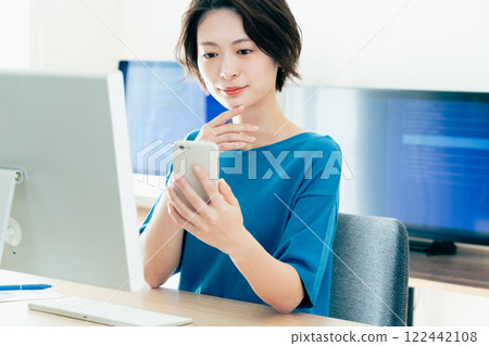 操作一個智能手機的少婦在辦公室 122442108