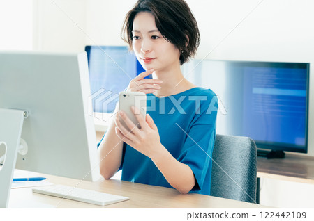 操作一個智能手機的少婦在辦公室 122442109