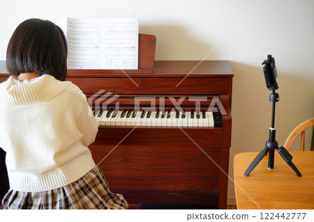 An 11-year-old girl in the fifth grade of elementary school taking online piano lessons 122442777