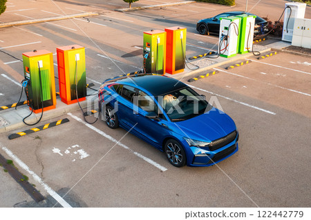 Modern vehicle receives electricity at public charging point. Parking lot equipped with plugs and connectors for quick replenishing of energy 122442779
