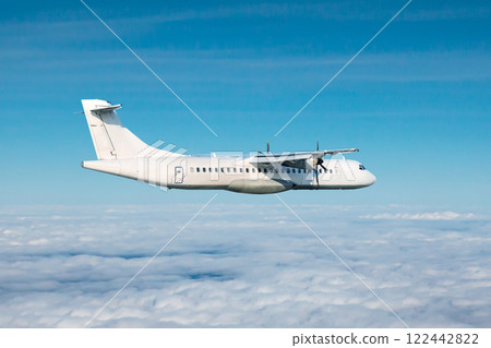 White passenger turboprop airplane flying in the air above the clouds White passenger turboprop airplane flying in the air above the clouds 122442822