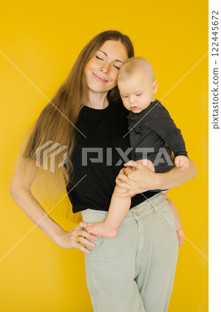 Young woman is holding boy baby in her arms. Warm and loving moment between mother 122445672
