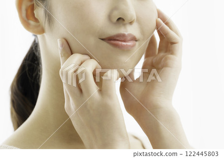 Close-up of a smiling young woman wearing a tank top on a white background with both hands on her cheeks, from the nose down, beauty Close-up of a smiling young woman wearing a tank top on a white background with both hands on her cheeks, from the nose down, beauty 122445803