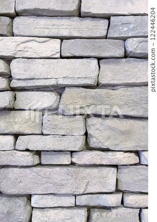Textured Stone Wall Background.A close-up view of a textured stone wall. The wall is constructed from irregularly shaped, light-colored stones that are stacked in a horizontal pattern. Textured Stone Wall Background.A close-up view of a textured stone wall. The wall is constructed from irregularly shaped, light-colored stones that are stacked in a horizontal pattern. 122446204