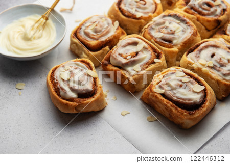 Freshly baked cinnamon rolls topped with cream cheese frosting and almond slivers Freshly baked cinnamon rolls topped with cream cheese frosting and almond slivers 122446312