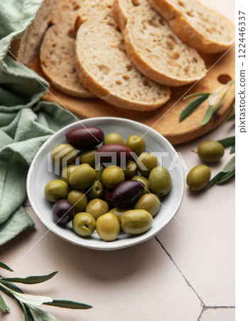 Sliced loaf of bread with green and black olives in a bowl on kitchen table 122446337
