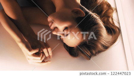 Beauty portrait. Female tenderness. Peaceful gorgeous sensual brunette woman with perfect face skin lying sleeping on light background. 122447023