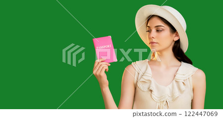 Upset tourist woman in summer hat holding pink passport international id document isolated on green copy space background. 122447069