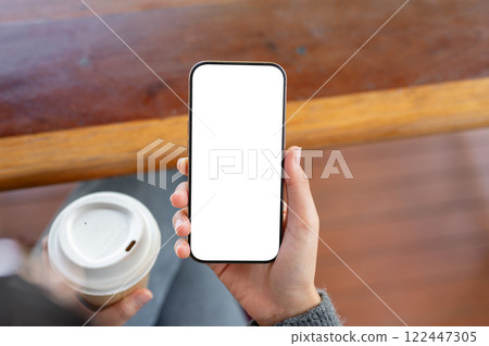 A close-up of a woman using her smartphone while sitting in a coffee shop. 122447305