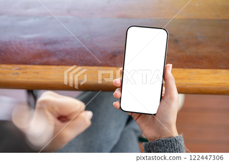 A woman holding a phone and clenching her fist in anger as she reacts to a video she is watching. 122447306