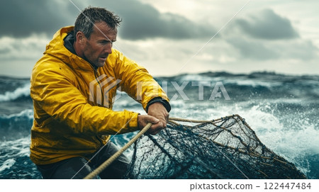 Fisherman in a yellow raincoat hauling a fishing net amidst rough ocean waves 122447484