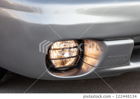 Front bumper fog lamp view of silver car after cleaning before sale in a workshop for repair and detailing vehicles auto service industry. Road safety while driving. Transportation lighting. 122448134