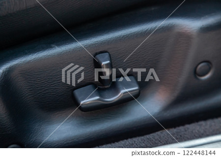Buttons for adjusting the seat horizontally in height by tilting backrest with black leather upholstery in the car after cleaning and detailing in the vehicle repair workshop. Auto service industry. Buttons for adjusting the seat horizontally in height by tilting backrest with black leather upholstery in the car after cleaning and detailing in the vehicle repair workshop. Auto service industry. 122448144