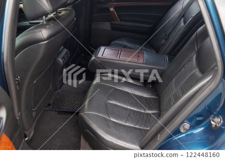Clean after washing the rear passenger seats of matte black genuine leather inside the interior of an expensive SUV, preparation before selling the car. 122448160