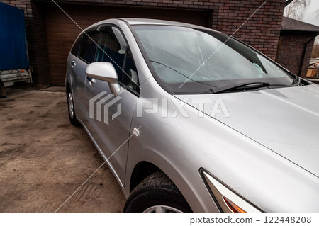 Close-up of the side right mirror and window of the car body silver sedan on the street parking after washing and detailing in auto service industry. Road safety while driving 122448208