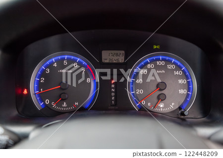 Car dashboard with red instrument circles with backlit arrows at night with a speedometer, tachometer with a mechanical gearshift gearbox to monitor the condition of the car on a black background. 122448209