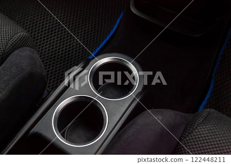 Interior view with two cupholders and armrest of black used car stands in the showroom after dry washing before sale Interior view with two cupholders and armrest of black used car stands in the showroom after dry washing before sale 122448211