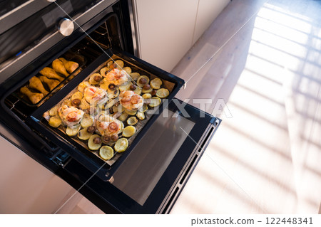 A baking tray with French-style pork, potatoes, mushrooms, and cheese, alongside baked chicken  122448341
