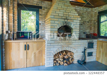 Brick-built fireplace in a countryside kitchen, surrounded by natural wood and rustic decor. 122448357