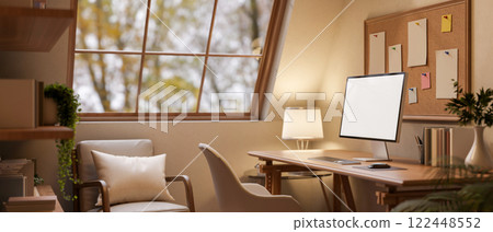A computer and decorative items on a hardwood desk in a warm, cozy room, illuminated by a lamp. A computer and decorative items on a hardwood desk in a warm, cozy room, illuminated by a lamp. 122448552