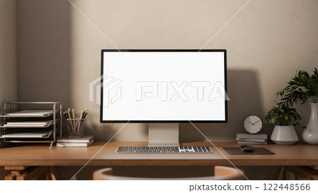 A front view of a computer and decorative plants on a hardwood desk against the wall in a cozy room. 122448566