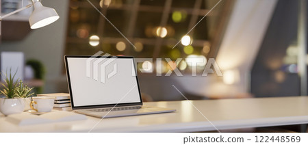 A white tabletop with a laptop and decorative items, set in a cozy contemporary room at night. 122448569