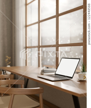 A laptop on a wooden table, positioned by a window with a snowy view, set in a cozy, minimalist cafe 122448588