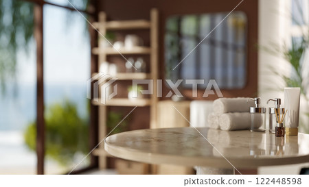 A round marble table features towels and bath products, set in a modern, brown bathroom. A round marble table features towels and bath products, set in a modern, brown bathroom. 122448598