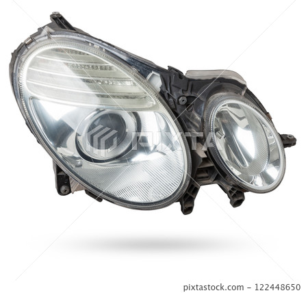 Stylish xenon headlight of a German car - optical equipment with a lamp inside on a white isolated background. Spare part for auto repair in a car workshop. Stylish xenon headlight of a German car - optical equipment with a lamp inside on a white isolated background. Spare part for auto repair in a car workshop. 122448650