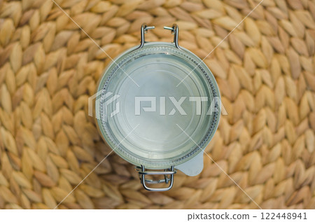 Empty glass jar with metal lid, top-down view, on woven wicker placemat. High quality photo 122448941