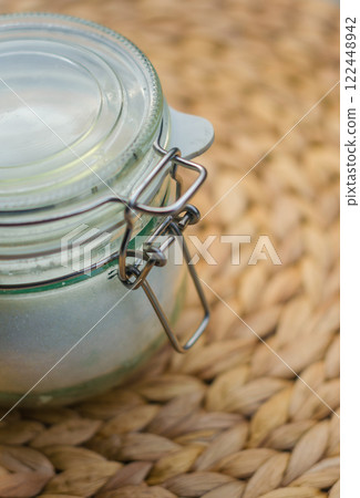 Glass jar with metal clasp on woven mat, rustic kitchen storage container. High quality photo Glass jar with metal clasp on woven mat, rustic kitchen storage container. High quality photo 122448942