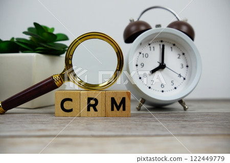 Magnifying glass and alarm clock with wooden blocks alphabet letters CRM text message on wooden background Magnifying glass and alarm clock with wooden blocks alphabet letters CRM text message on wooden background 122449779
