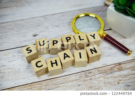 Magnifying glass with wooden blocks alphabet letters SUPPLY CHAIN text message on wooden background 122449784